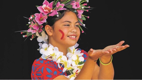 A Pasifika child wreathed in a smile and flowers.