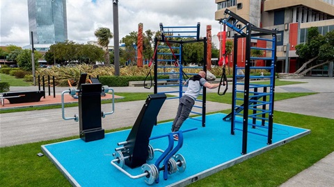 Man works out on outdoor gym in Te Marae o Hine.