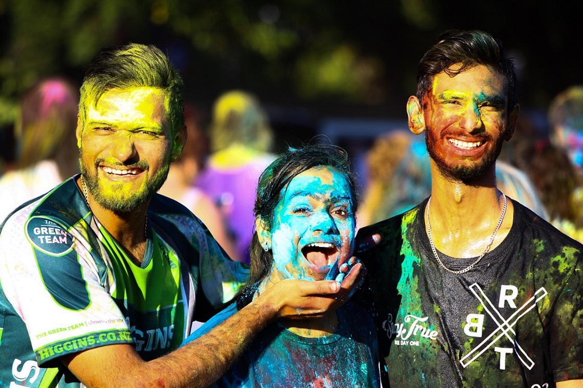 Picture shows three people with colourful face painting smiling