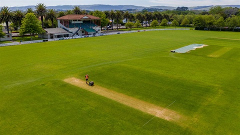 Photo shows aerial image of worker maintaining the cricket pitch 