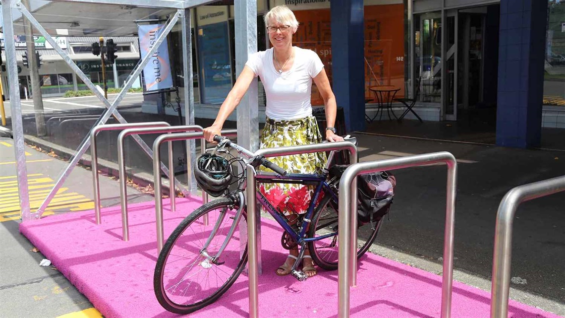 A woman parks her bike in the new pink-floored bike shelter.