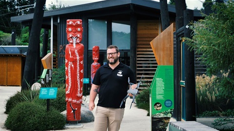 Bearded man in Wildbase uniform holding a drone near the outdoor rehabilitation aviaries.
