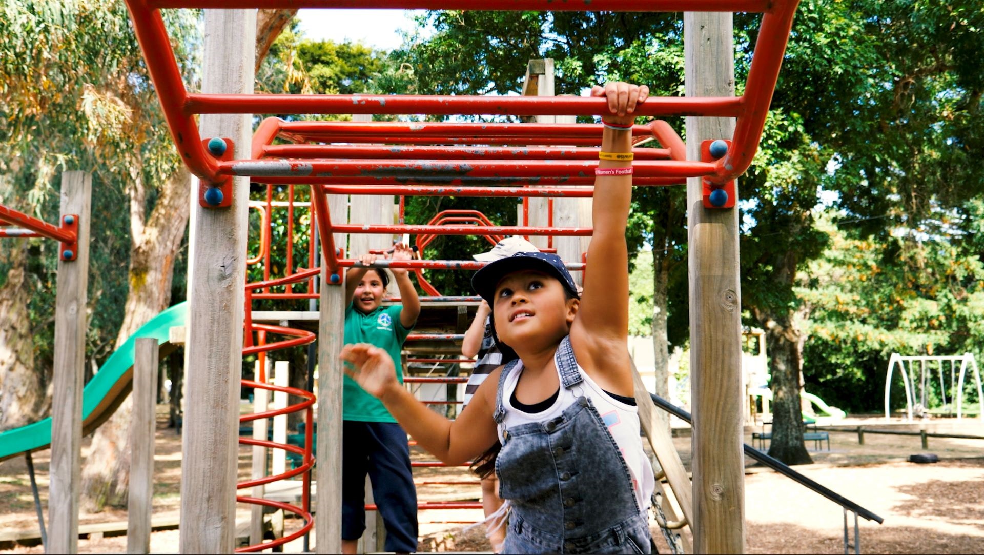 Photo shows children swinging on climbing bars in the Domain playground.