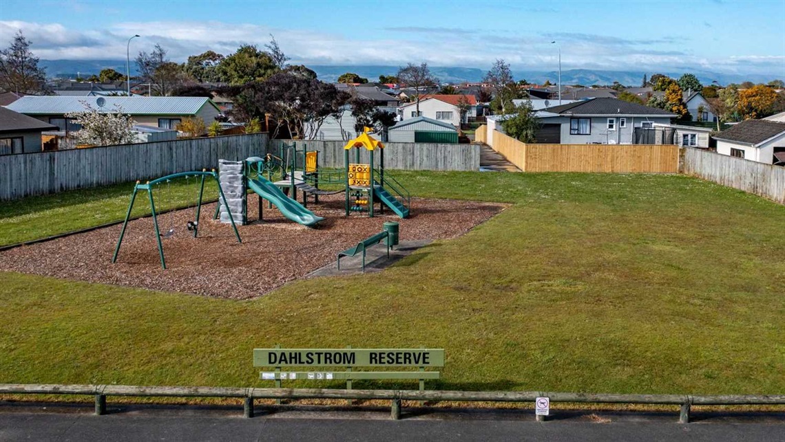 Picture shows playground in a neighbourhood reserve and wooden fences between the park and the homes along its border.