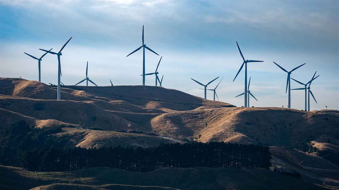 Photo shows hills with electricity-generating windmills whirring away.