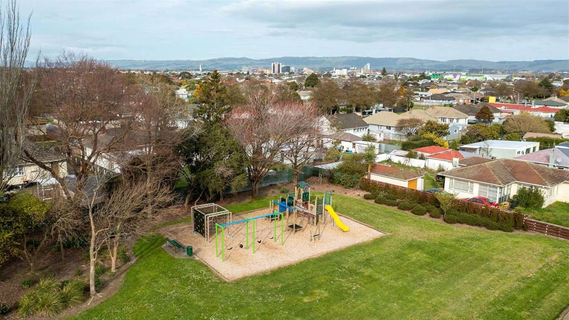 Photo shows the new playground at Gloucester Street Reserve, with climbing frames, a slide and swings.
