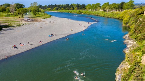 People swimming in the river and sunbathing at Ahimate Beach.