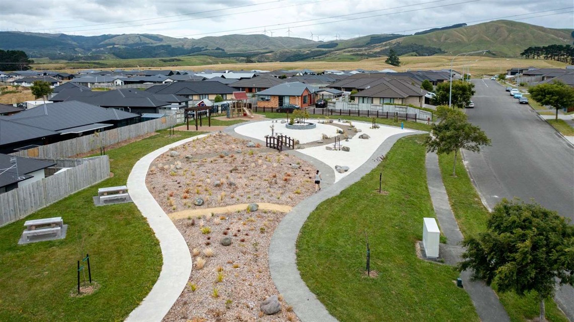 Photo shows a new neighbourhood park, with a small playground, Japanese-style garden and picnic tables.