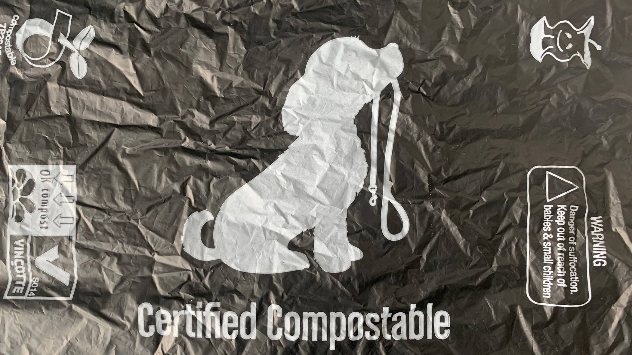 Photo shows compostable dog poo bag. It's printed with a dog holding a lead, eco-symbols and the words 