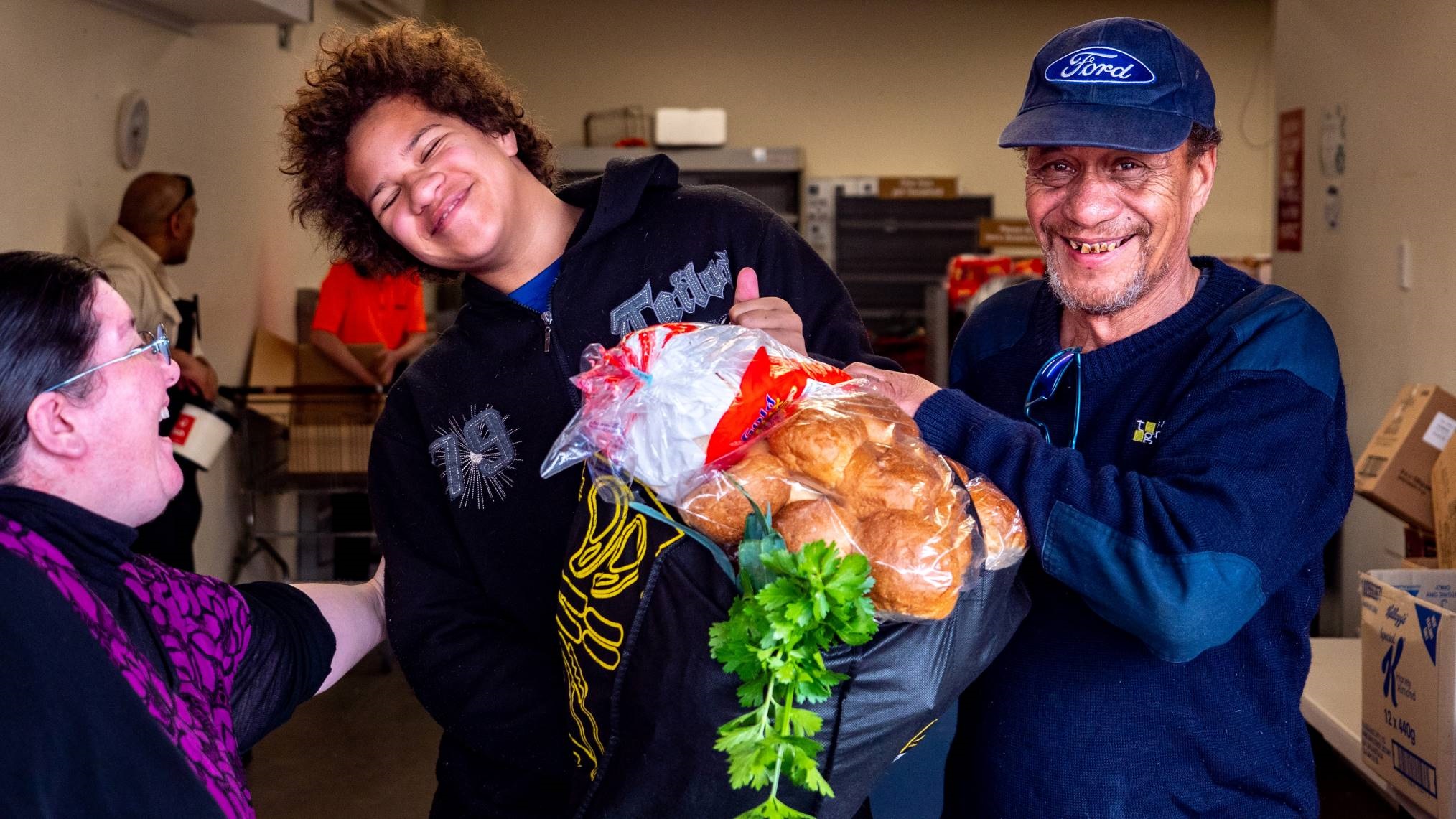 Photo shows food rescue pioneer Rebecca Culver and two smiling patrons of her charity, which both prevents food waste and provides free food to people who need it.