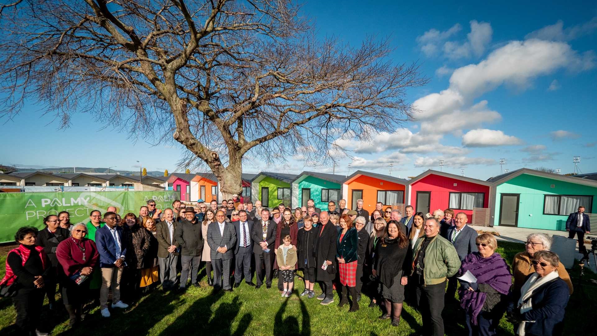 Large group of residents, iwi, politicians and council officers gathered in front of the new homes.