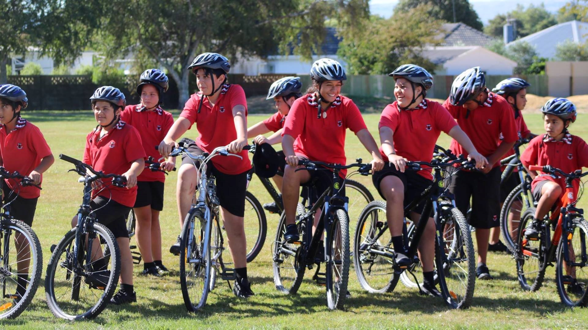 Photo shows group of school pupils wearing helmets and riding bikes.