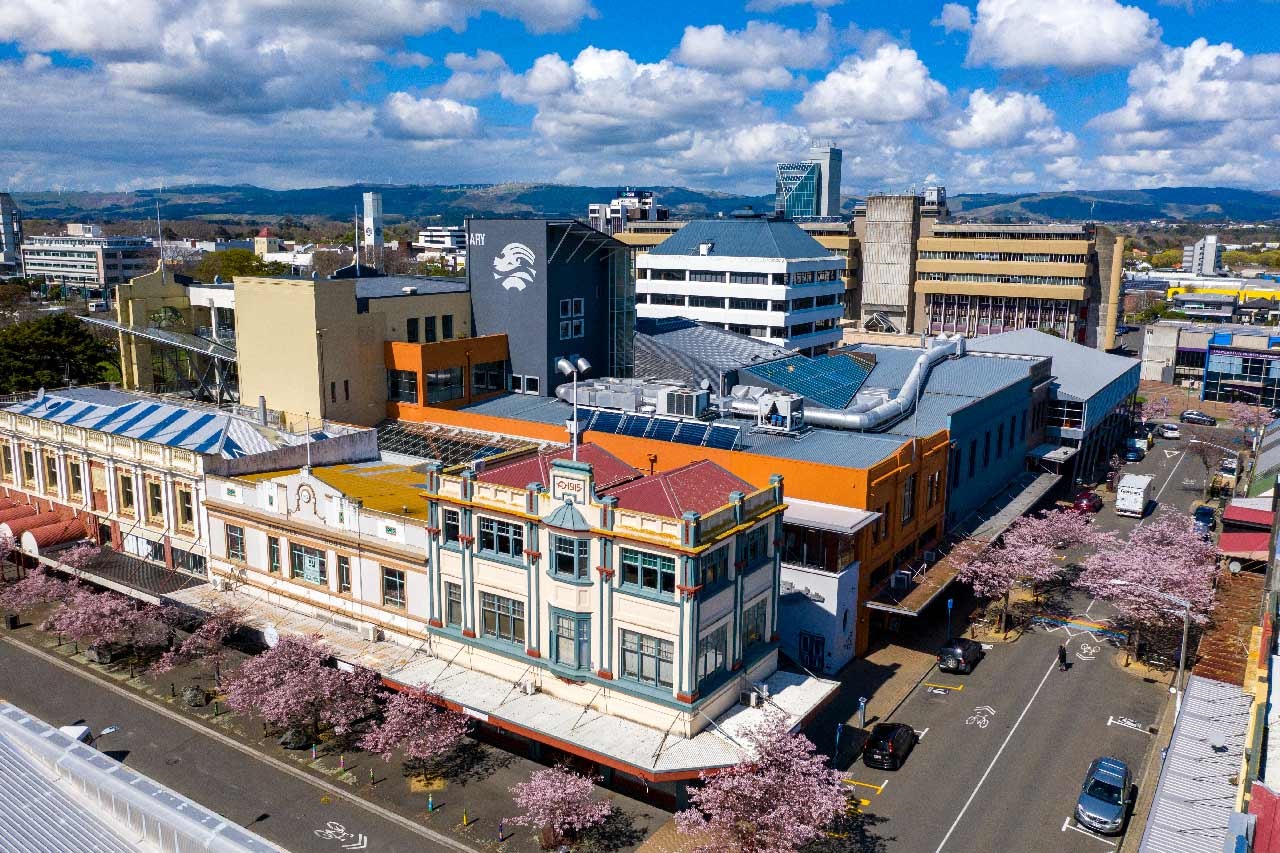 Image shows aerial views of buildings at a cross of two roads.