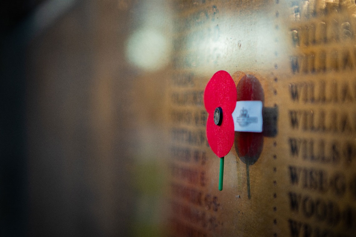 Image shows an Anzac poppy on a memorial wall