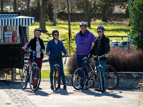 image shows four senior cyclists resting next to a coffee cart