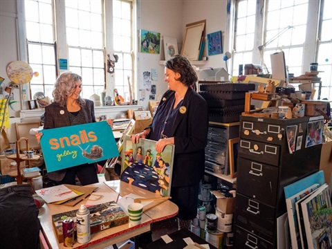 image shows two women holding a banner among books.jpg