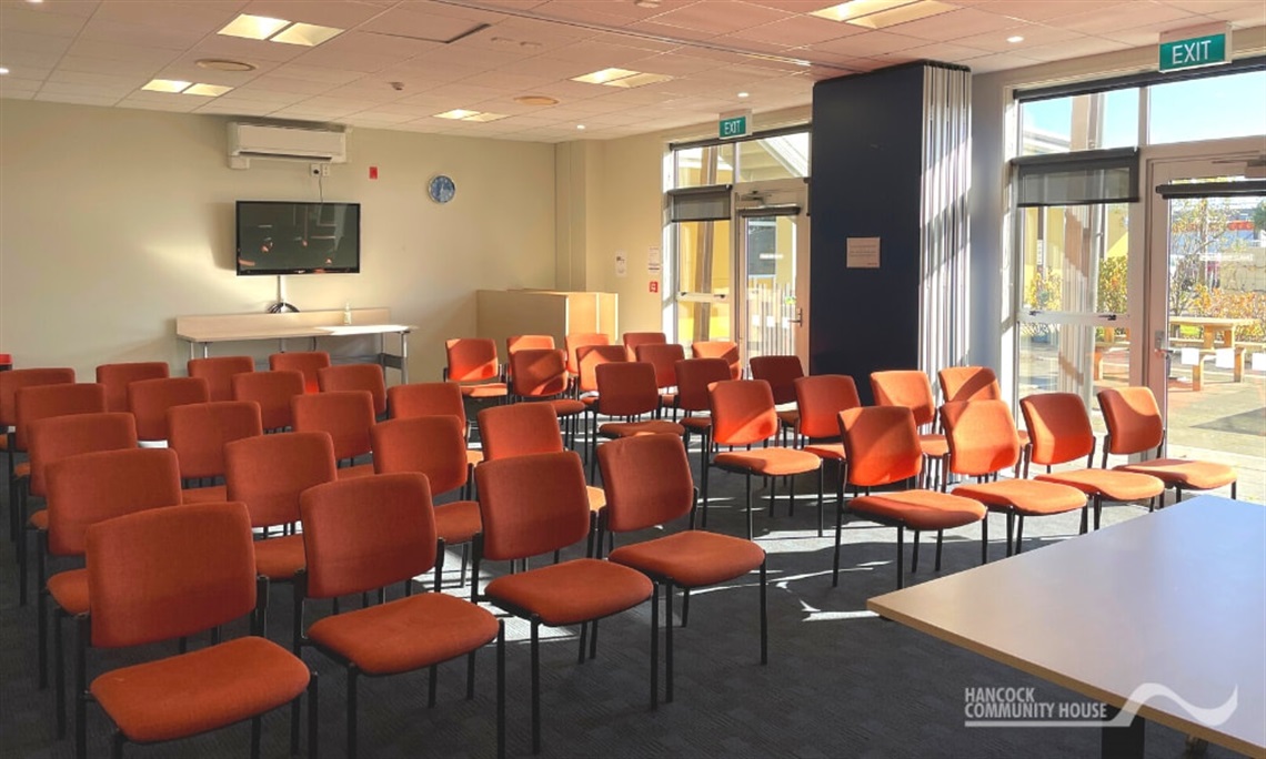 Image shows an empty hall with dozens of orange chairs