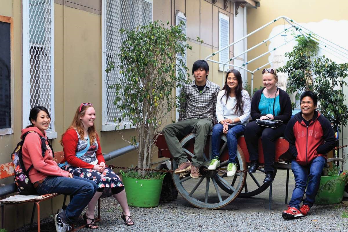 Multicultural group of young people laughing and talking amongst themselves.