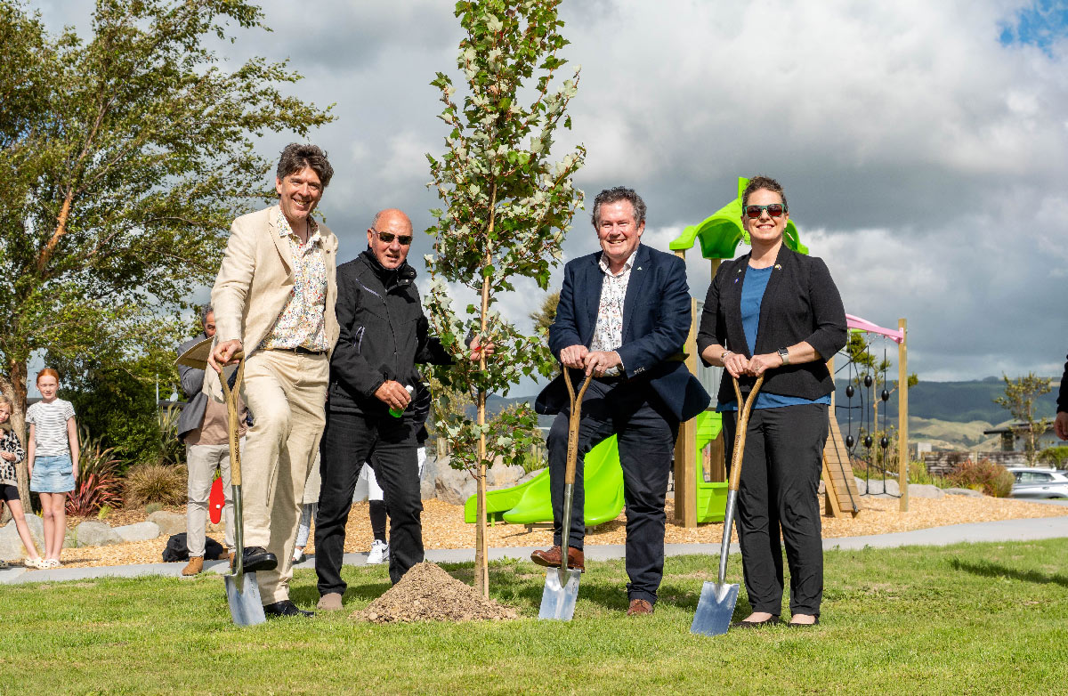 photo of four people standing beside a newly planted tree