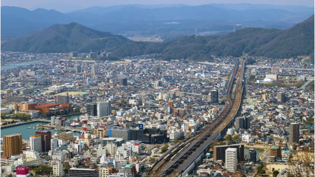 image shows aerial view of a city by mountains