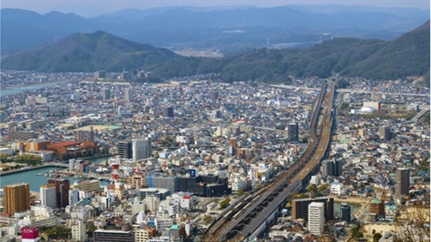 image shows aerial view of a city by mountains