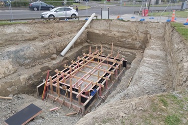 A closer look at the deep hole in the ground, with concrete now poured at the base and timber supports ready for the next stage.