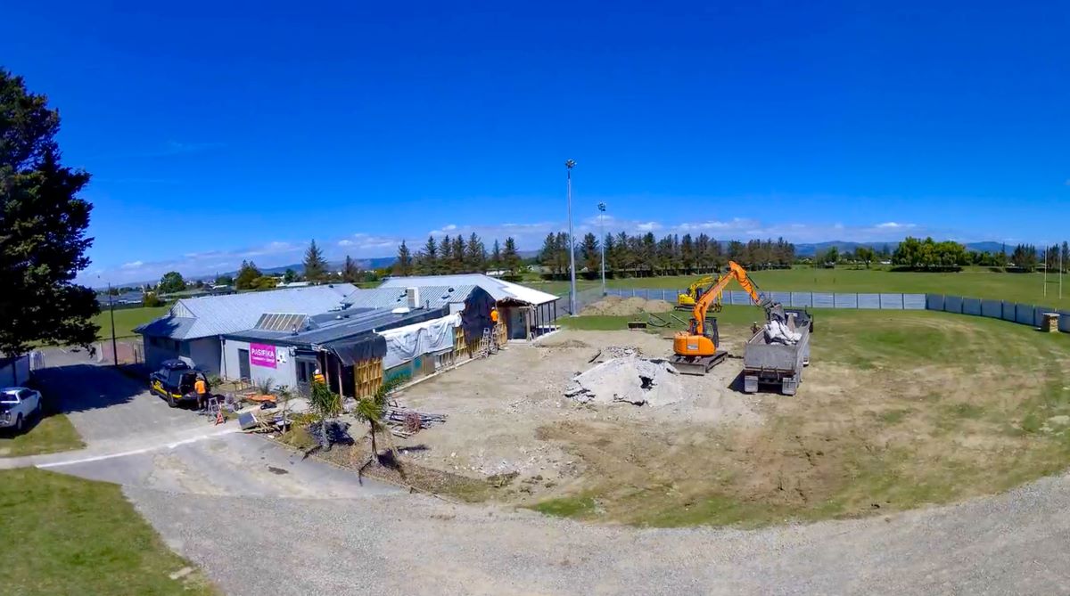 Heavy machinery clearing demolished building materials from the site.