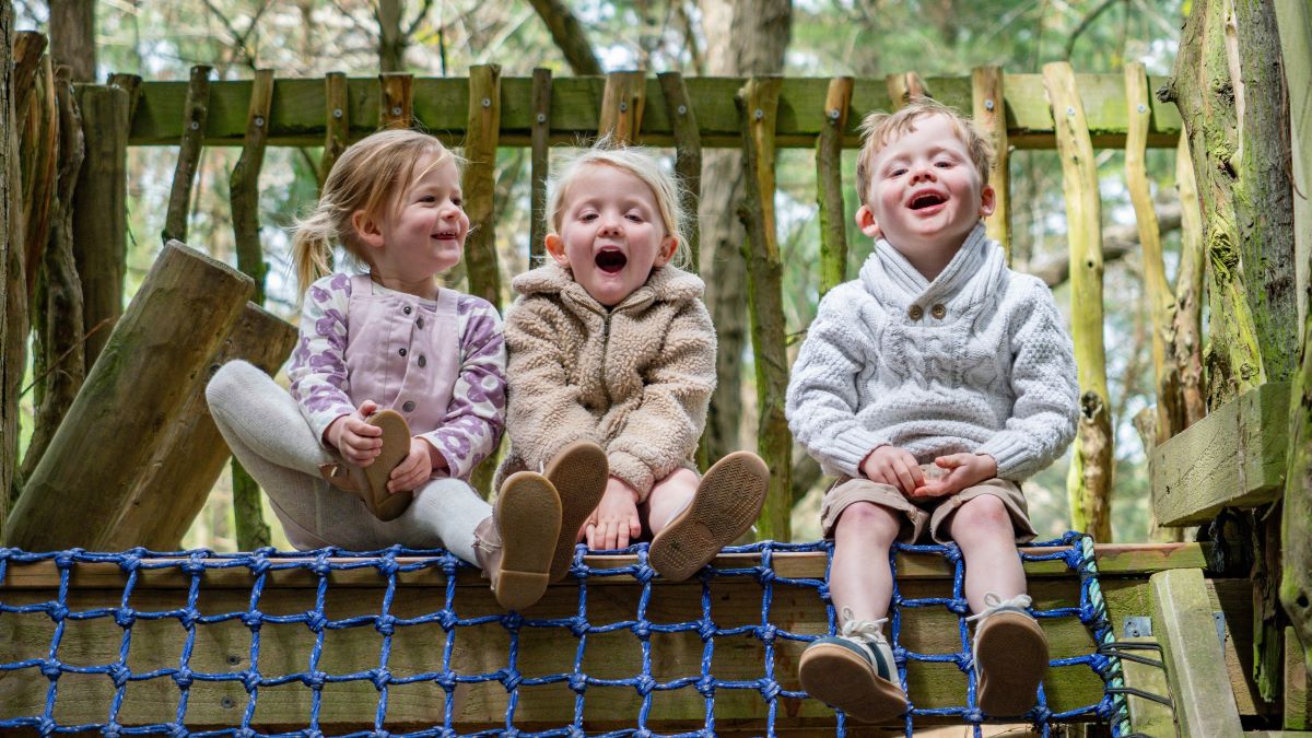 Grinning children playing in the fort at Albert Street Forest.