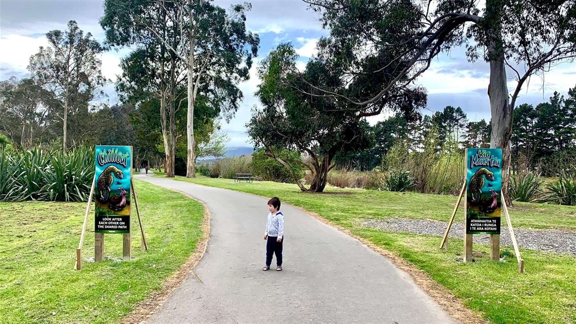 Photo shows small boy looking at one of the new bilingual signs along the river pathway.