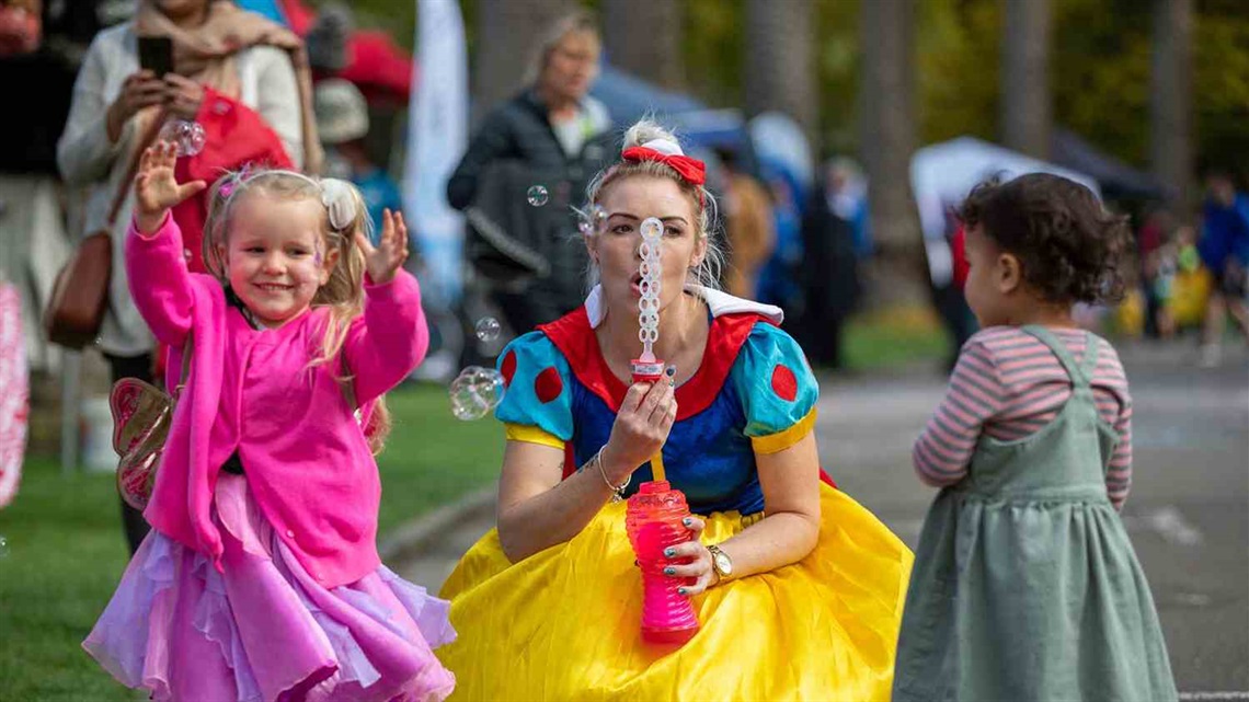 Two children play with bubbles blown by a Disney Princess.