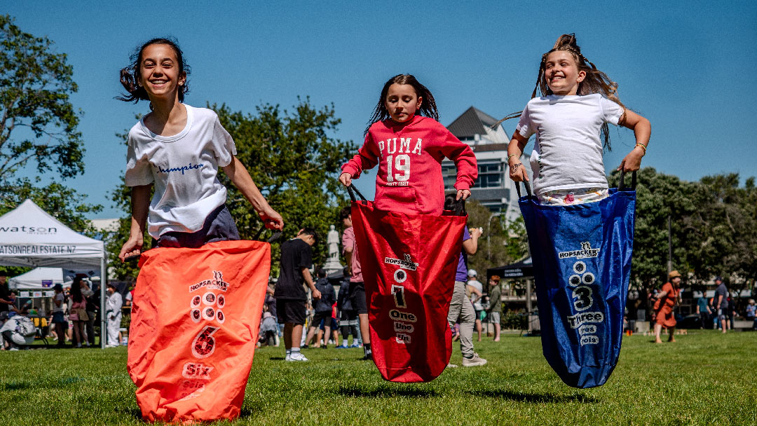 Image of kids jumping on the grass in front of commercial buildings