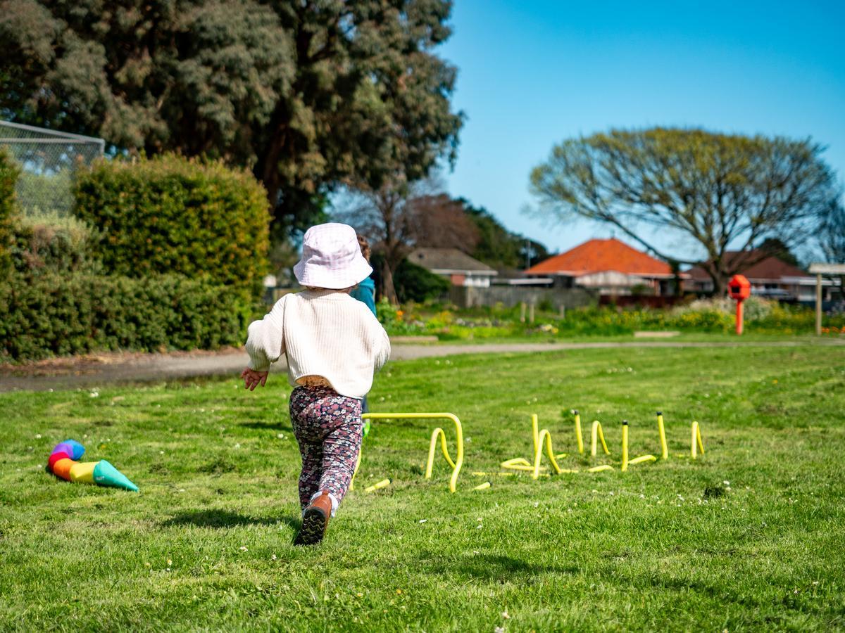 Image shows a toddler running on grass under winter sun