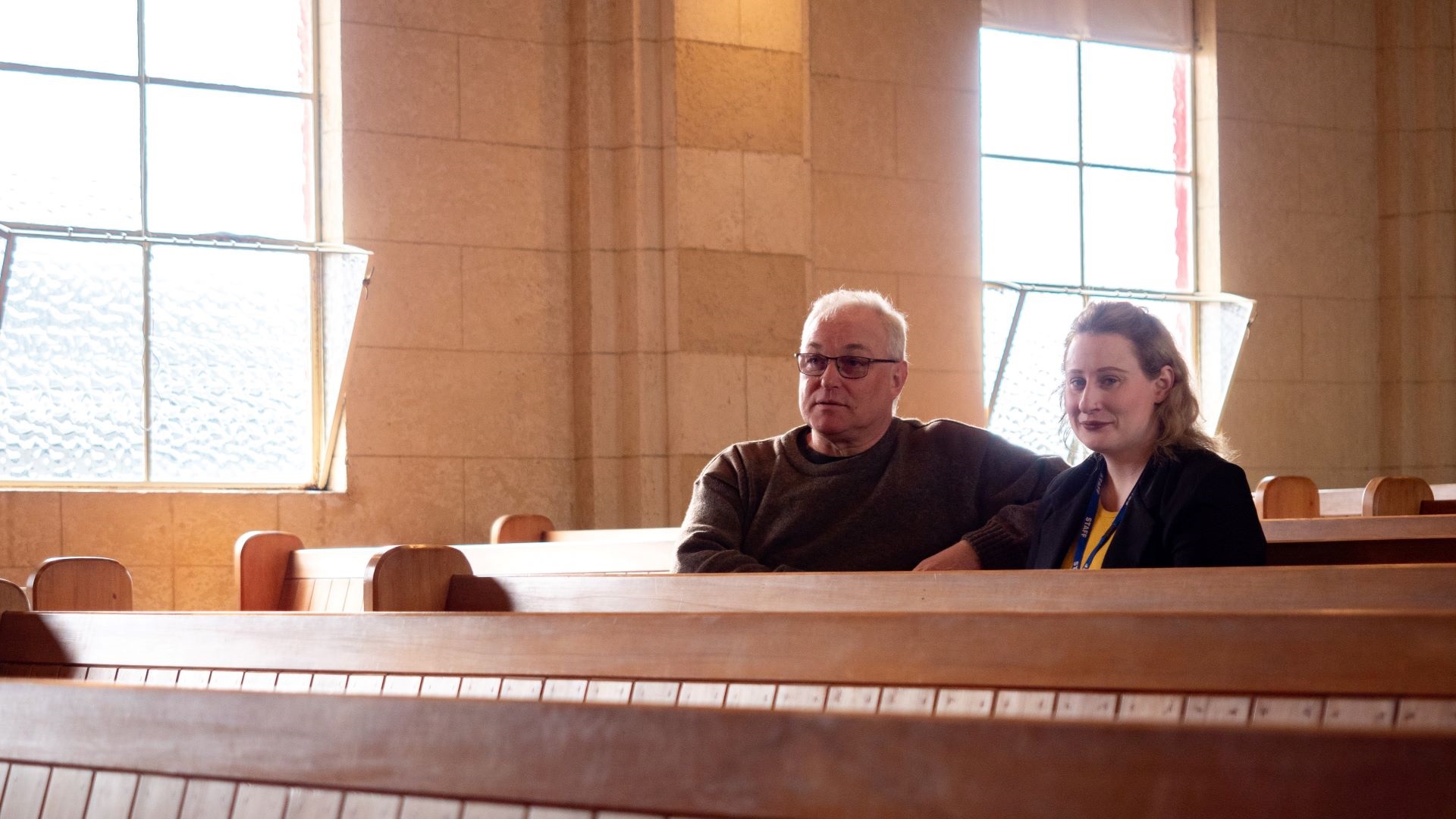 Heritage building owner Ben Millar with Council planner Victoria Edmonds sitting on a pew inside the recently strengthened church.