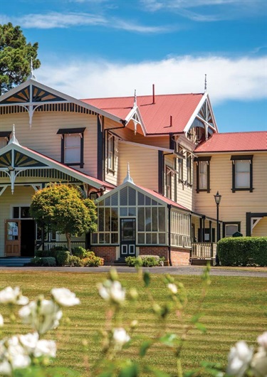 image shows a historical homestead behind a bunch of flowers