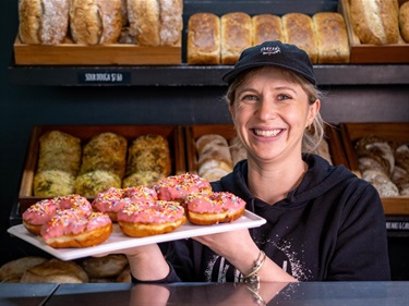 image shows a happy woman holding a plate of donuts