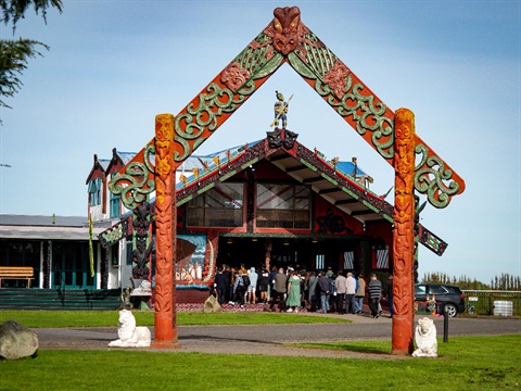 Image shows a group of students attending a powhiri at the entrance of a marae