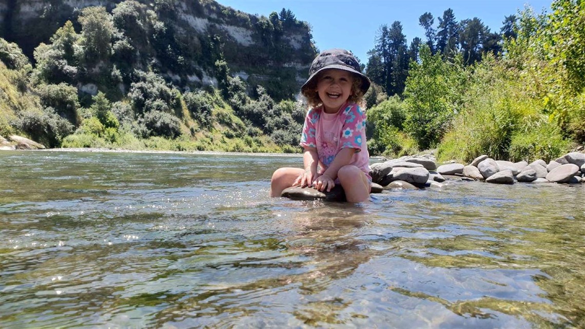 Child playing in shallow water in a river.