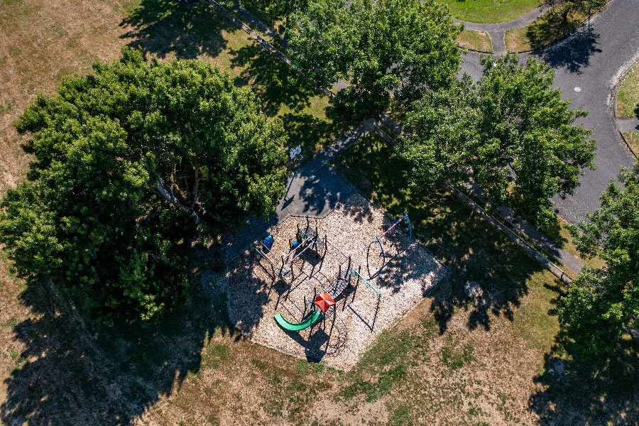 Image shows aerial view of a playground at the end of a cul-de-sac surrounded by trees