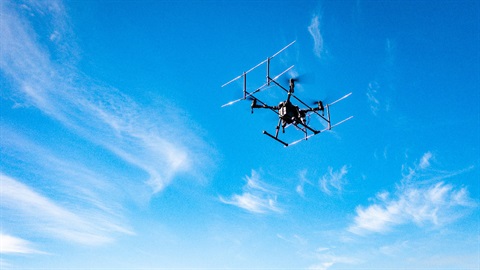 Photo shows a drone flying in the blue sky.