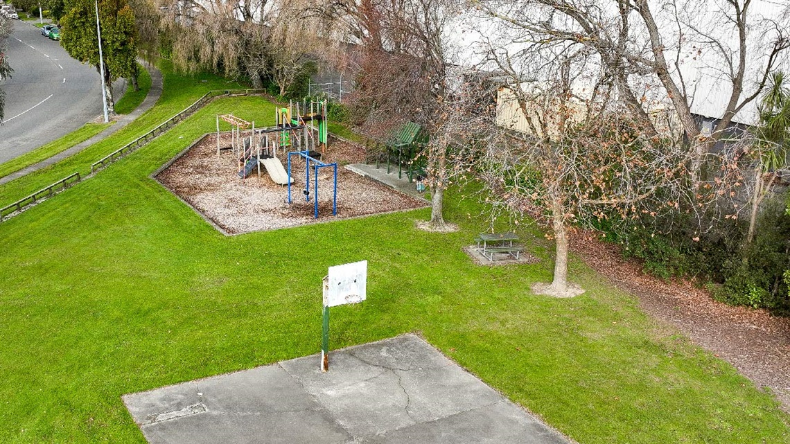 Image shows aerial view of a playground and a basketball hoop on roadside.