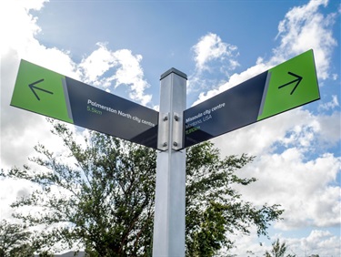 A directional sign at Missoula Reserve points towards Palmerston North city centre and Missoula city centre, showing the distance to each location.