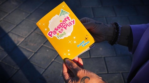 Image shows a hand holding a yellow passport to play palmy