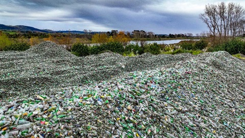 Colourful glass bottles pile up by the river