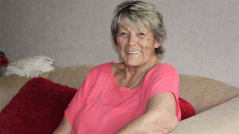 Smiling older woman in brightly coloured shirt.