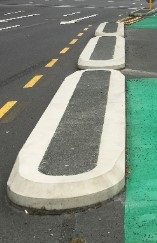 Image shows three concrete blocks seperating cycleway and the main road