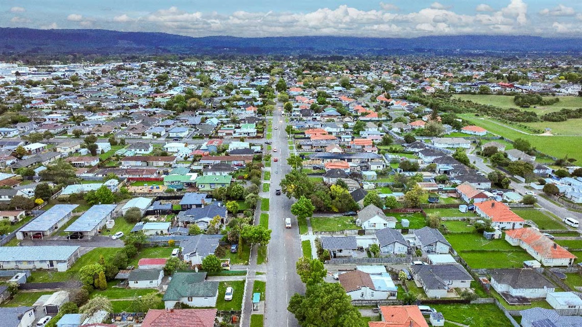 Photo of aerial view of a long straight road stretching through residential area