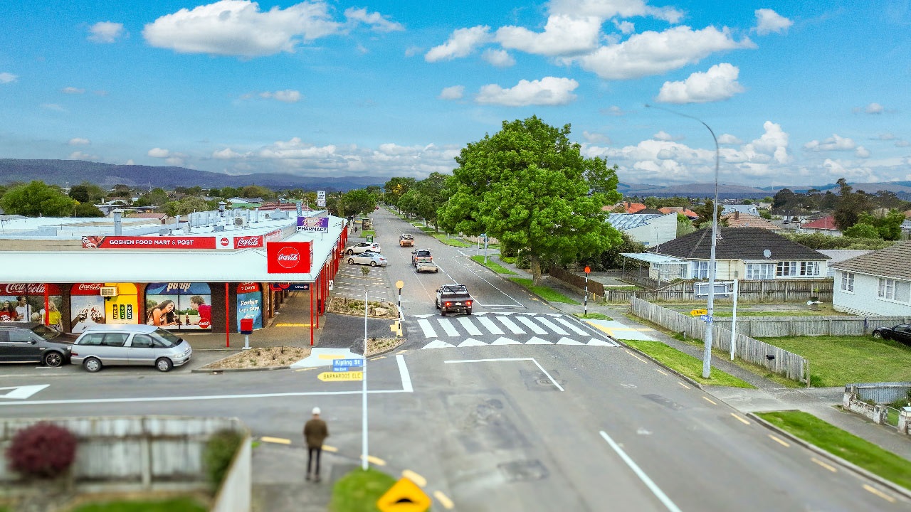Photo of aerial view of a three-way cross with a raised pedestrian crossing and shops on road side.