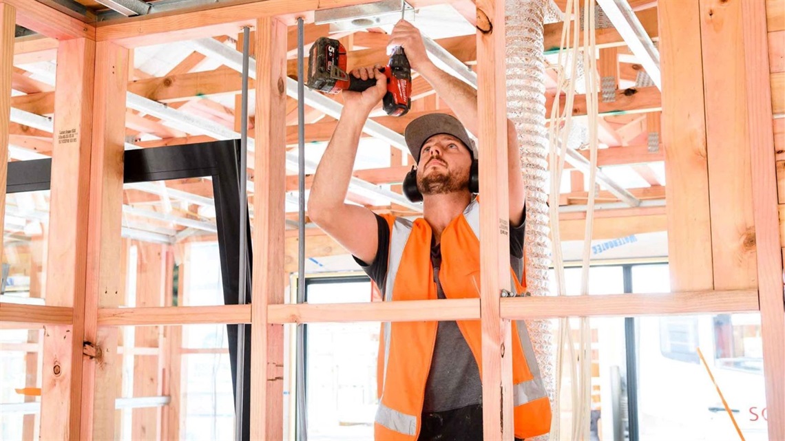 Construction worker nailing timber-framed structure.