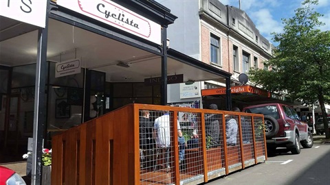 Parklet from the road with cars parked either side.