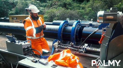 A worker in hi-vis connecting the new duplicate pipe to the city water supply.